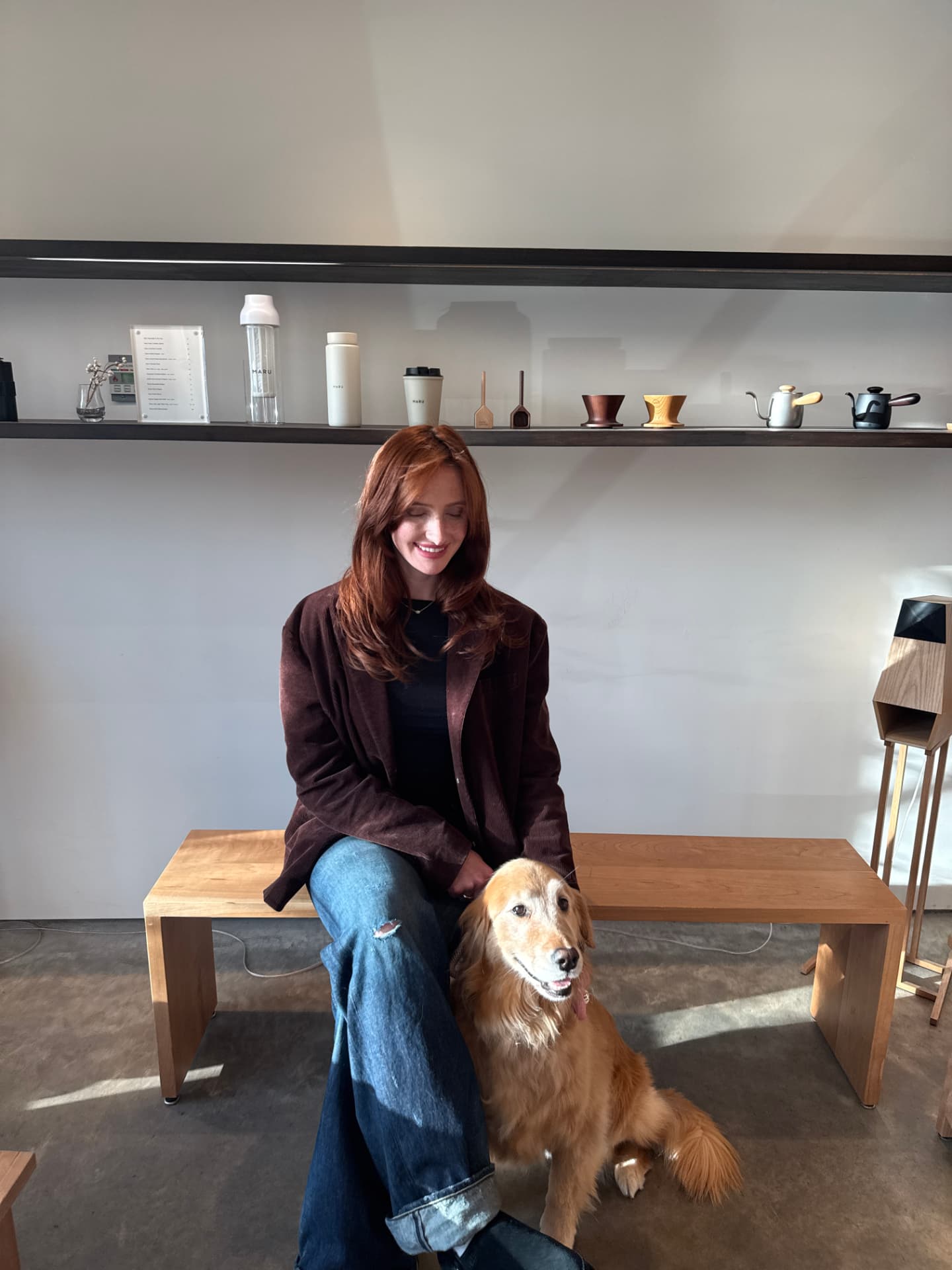 One of the founders smiling on a bench with her golden retriever